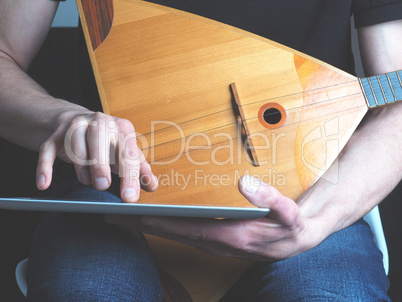 Musician with a balalaika and tablet computer