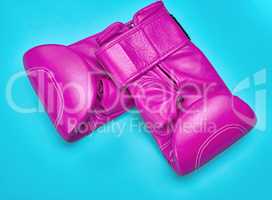 pair of pink leather boxing gloves on a blue background