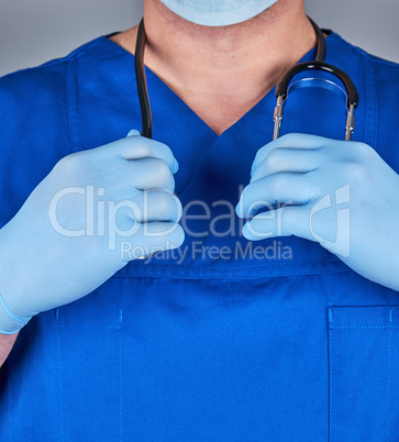 doctor in a blue uniform and old latex gloves holding a black st