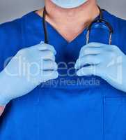 doctor in a blue uniform and old latex gloves holding a black st