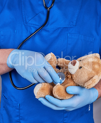 doctor in blue uniform and old latex gloves holding a brown tedd