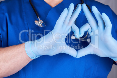 doctor in blue uniform and old latex gloves showing heart gestur