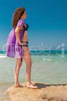 A girl in a bathing suit and a lilac translucent cape.