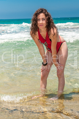 Girl in a red bathing suit fooling standing in the sea