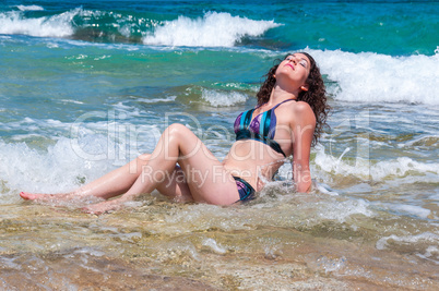 Girl lying in the coastal waves, closed her eyes to pleasure
