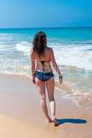 The girl in the blue bikini goes on the beach