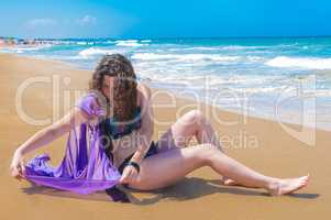 Girl neatly spreads a wet cape on the sand.