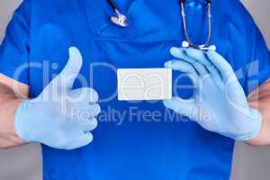 male doctor wearing blue latex gloves is holding a blank white p
