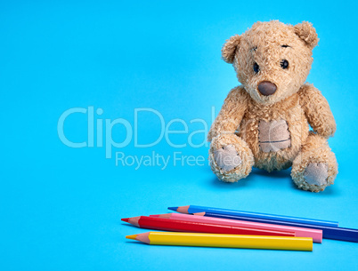 brown teddy bear and multicolored wooden pencils