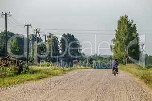 Landscape with rural road and man on moped..