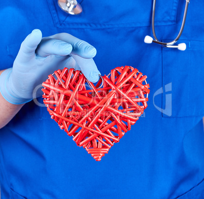 doctor in blue uniform  holds a big red heart