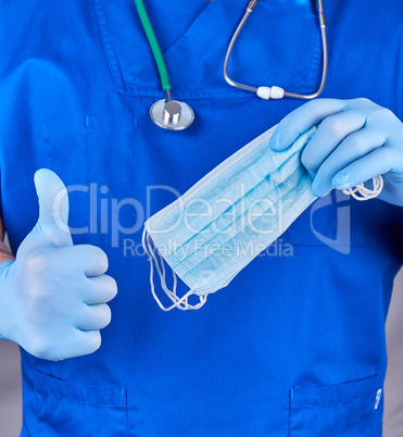 doctor in uniform and in blue latex gloves keeps sterile masks,