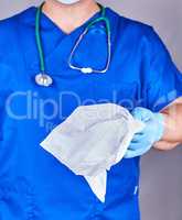 doctor in blue uniform and sterile latex gloves holding a white