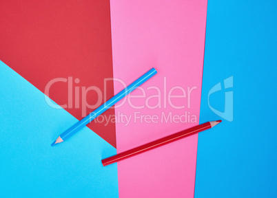 red and blue wooden pencils on color abstract background