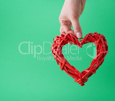 female hand holding red wicker decorative red heart