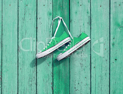 pair of green textile sneakers hanging on a nail on the wall