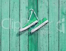 pair of green textile sneakers hanging on a nail on the wall