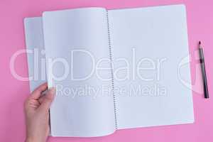 empty open notebook in a cell and a female hand