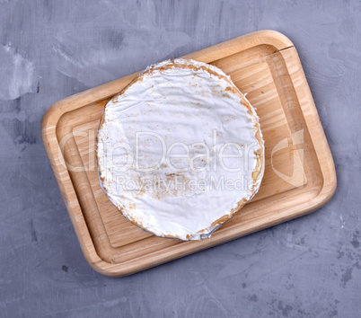 round piece of brie cheese on a wooden board