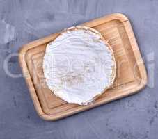round piece of brie cheese on a wooden board