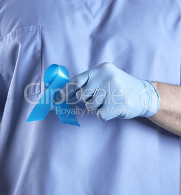 doctor in uniform and latex gloves holding a blue ribbon in his