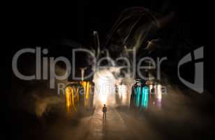 Silhouette of a man standing in the middle of the road on a misty night with giant glass bottles filled with electronic cigarette liquid. Colorful foggy clouds with light on background.