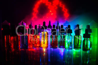 Vape concept. Smoke clouds and vape liquid bottles on dark background. Light effects. Useful as background or electronic cigarette advertisement.