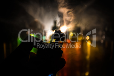 Vape concept. Electronic Cigarette vape explosion. Smoke clouds and vape liquid bottles on dark background. Light effects. Useful as vape advertisement.