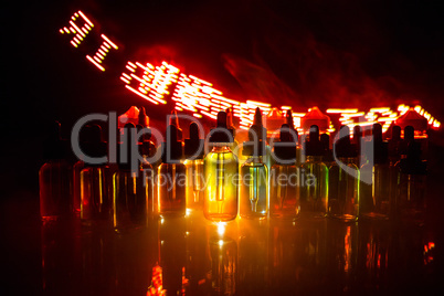 Vape concept. Smoke clouds and vape liquid bottles on dark background. Light effects. Useful as background or electronic cigarette advertisement.