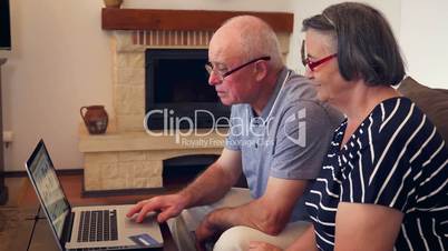 Senior couple shopping online using credit card on laptop