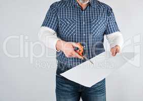 man in blue shirt scissors blank white sheet of paper
