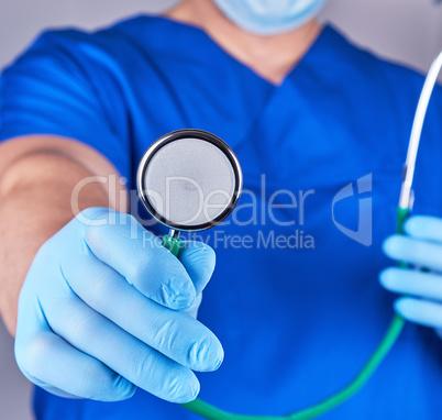 doctor in blue uniform and sterile gloves holding a medical stet