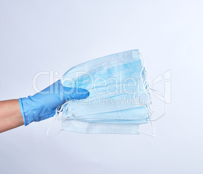blue sterile gloved hand holding a medical mask