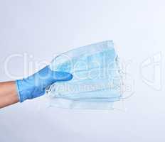 blue sterile gloved hand holding a medical mask
