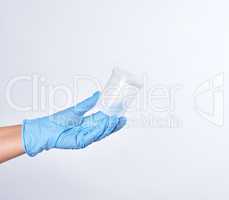 hand in a blue sterile glove holds a plastic container