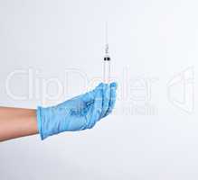 hand in a blue sterile glove holds a plastic syringe
