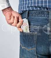 man in a blue plaid shirt and jeans puts paper American dollars