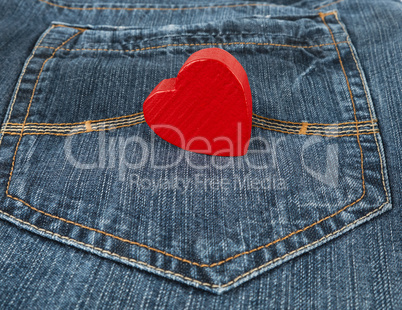 small red heart lies in the back pocket of blue jeans