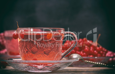 viburnum tea in a transparent cup with a handle and saucer