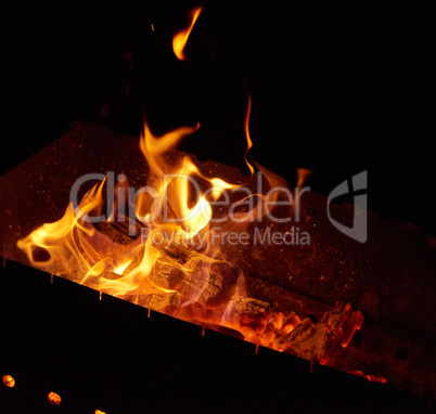 burning wooden logs in the fire at night