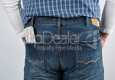 bundle of paper money in the back pocket of blue jeans
