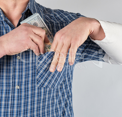 man in a blue shirt puts in a pocket a stack of paper money