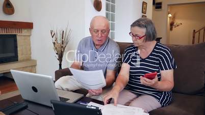 Senior couple calculating bills cost at home