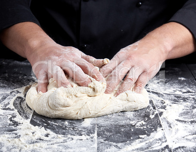 baker kneads white wheat flour dough