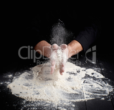 man's hands and splash of white wheat flour