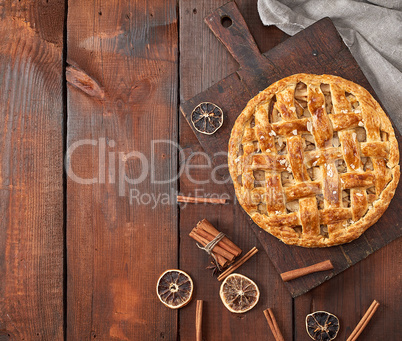 baked whole round apple pie on a brown wooden board