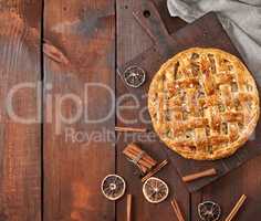 baked whole round apple pie on a brown wooden board