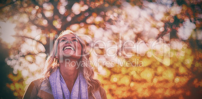 Smiling woman looking up against trees