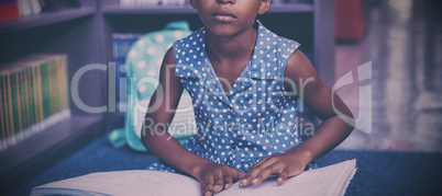 Girl reading braille book in library