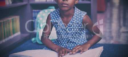 Girl reading braille book in library